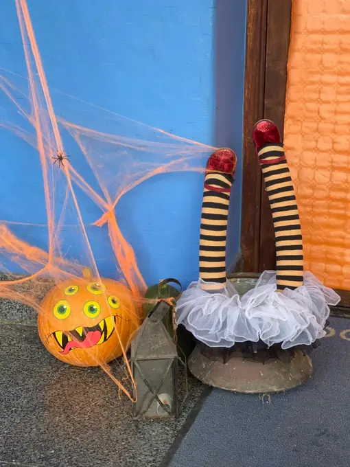 Una calabaza y piernas de bruja junto a una telaraña
