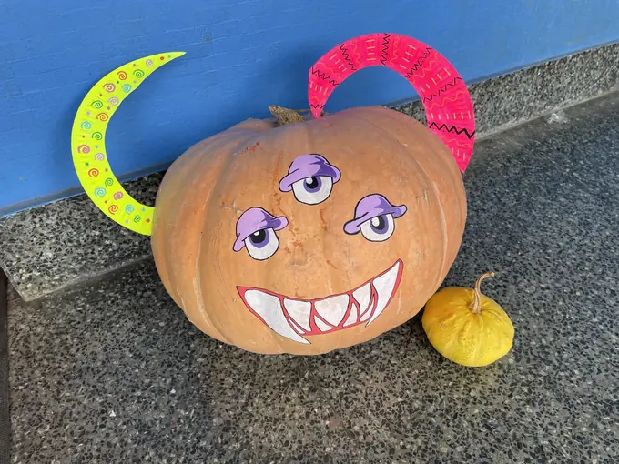 Una calabaza decorada con ojos y cuernos de colores